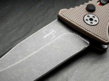 Рукоять ножа Boker Plus Strike Droppoint Coyote на фоне активной жизни для туристов путешественников в магазине экипировки для активного отдыха, походов, трекинга и альпинизма